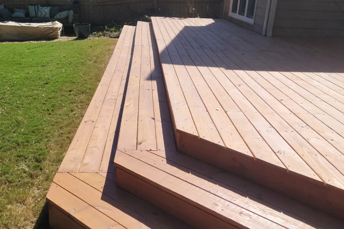 A finished pressure-treated deck with wide steps down to the lawn