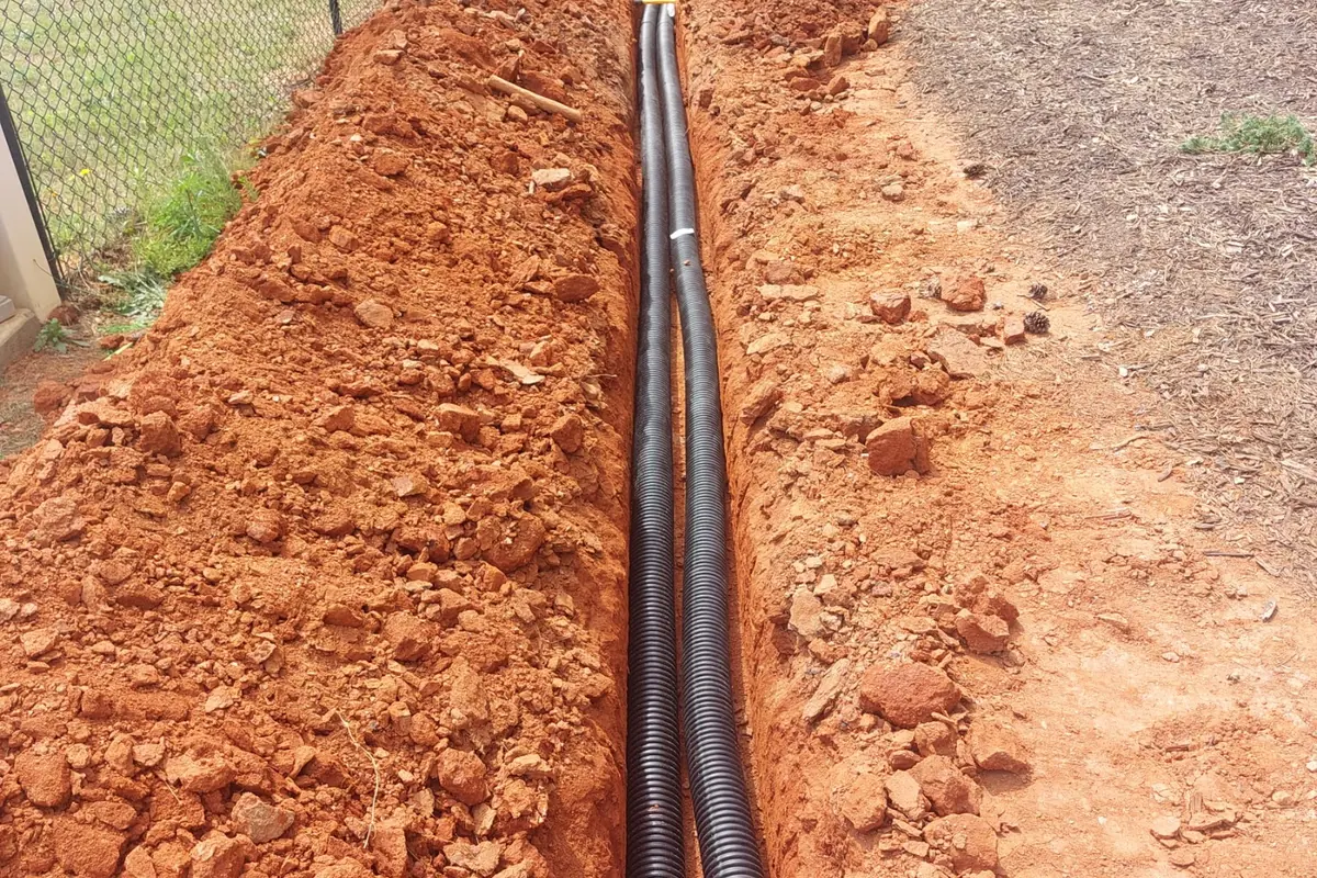 Corrugated drain pipe laid in an open trench cut through Georgia red clay