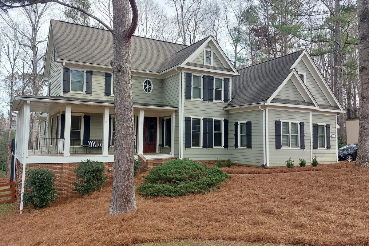 The front of a two-story home with wide landscape beds freshly covered in pine straw
